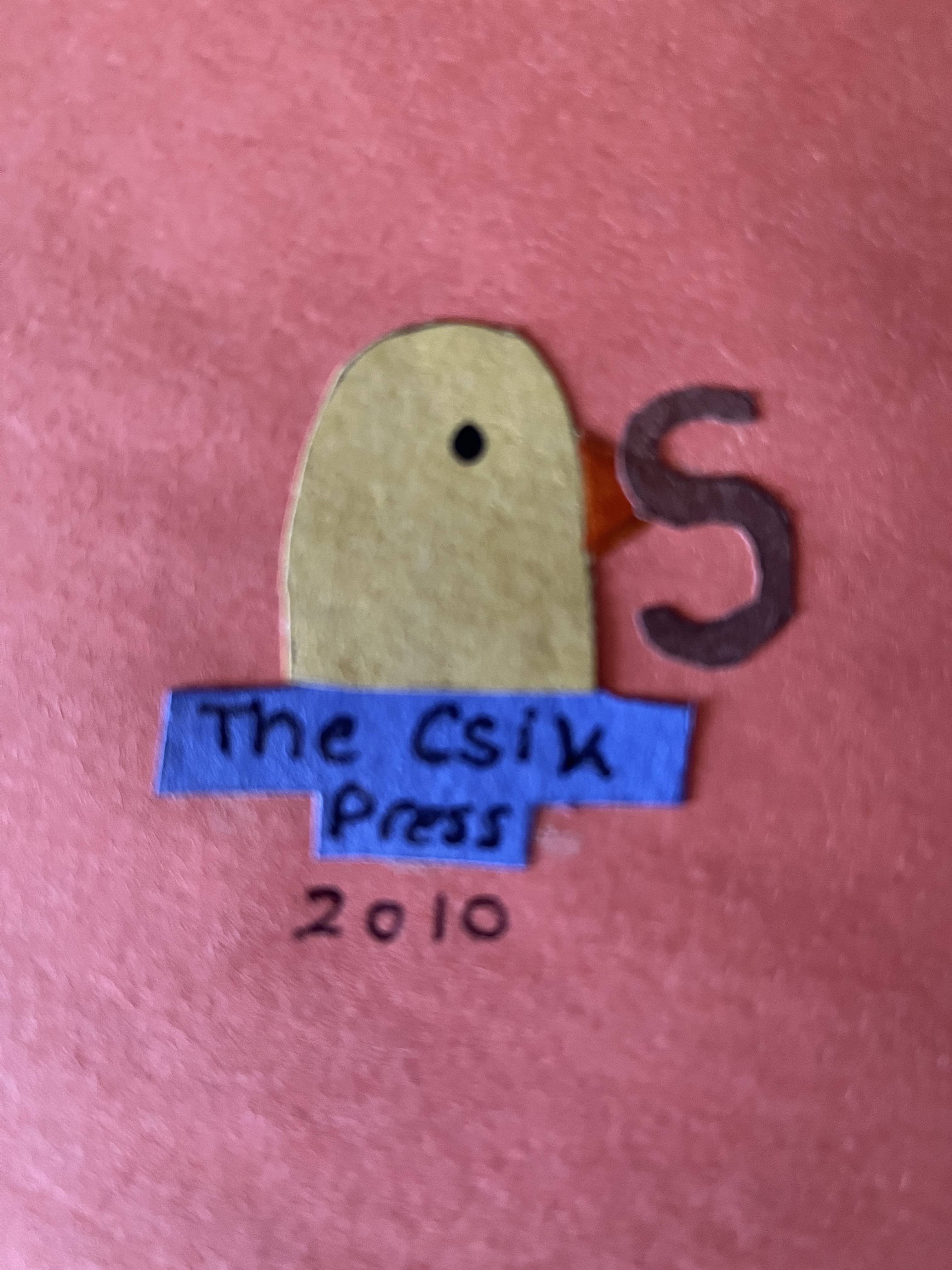 The back of a handmade card made of construction paper. A yellow chick with an orange beak holds an 'S'-shaped worm in its beak. It sits on top of the text, 'The Csik Press'. Below this, the year '2010' is written in pen.